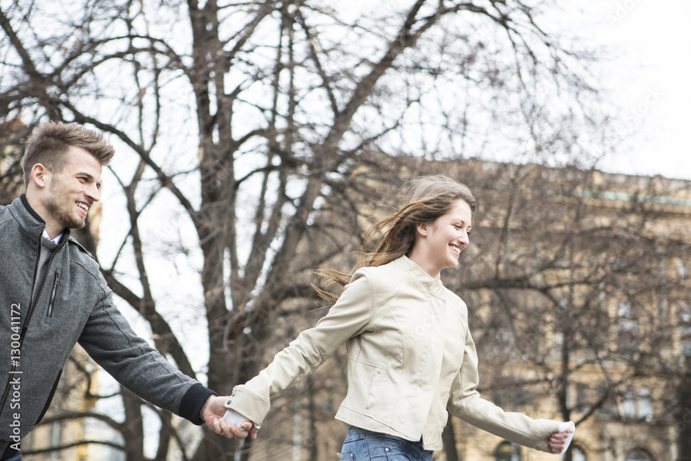 Smiling young man and woman holding hands and walking outdoors Smiling young man and woman holding hands and walking outdoors