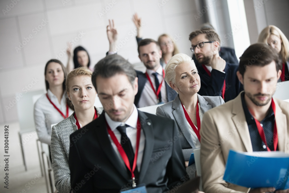 Thoughtful businesswoman sitting with colleagues in seminar hall Thoughtful businesswoman sitting with colleagues in seminar hall