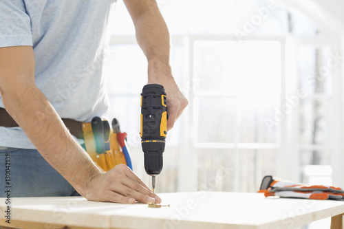 Konstfotografi Midsection of man drilling nail on table