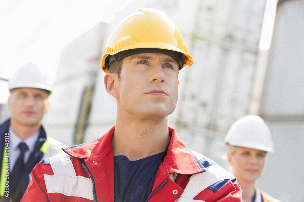 Confident male worker with colleague in background at shipping yard Confident male worker with colleague in background at shipping yard