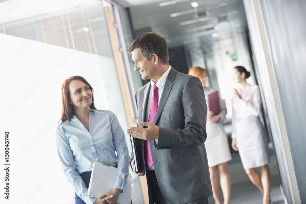 Businessman talking with female colleague while walking in office corridor Businessman talking with female colleague while walking in office corridor