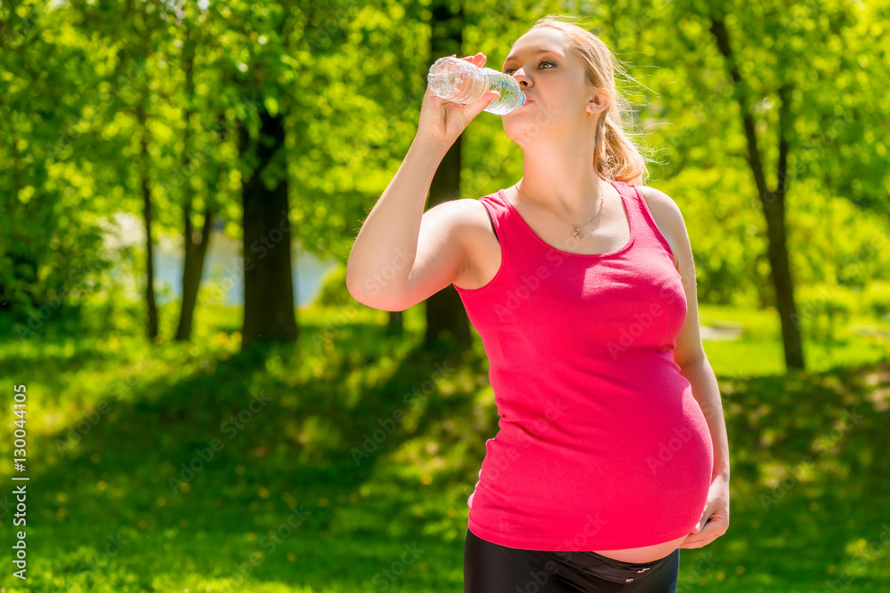 portrait of a pregnant woman drinking fresh water from a bottle portrait of a pregnant woman drinking fresh water from a bottle