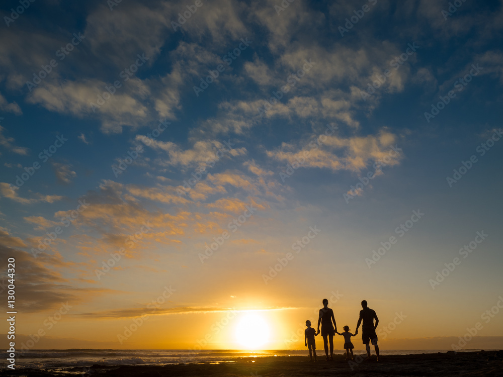 Family at sunset by the ocean. People hold hands and look at the