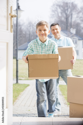 Happy father and son with cardboard boxes entering new home © moodboard