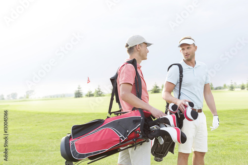 Male golfers communicating at golf course against clear sky © moodboard