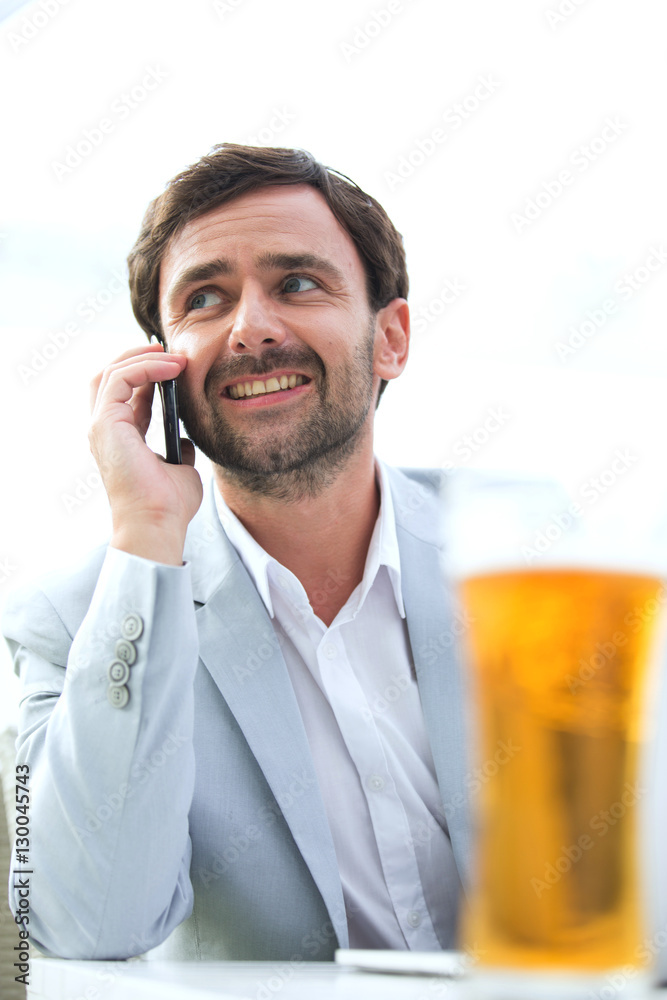 Happy businessman looking away while using mobile phone at outdoor restaurant Happy businessman looking away while using mobile phone at outdoor restaurant