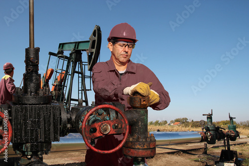 Fotografie Two Oil Workers Repair an Oil Well at Oilfield / Two workers repairing a oil pum