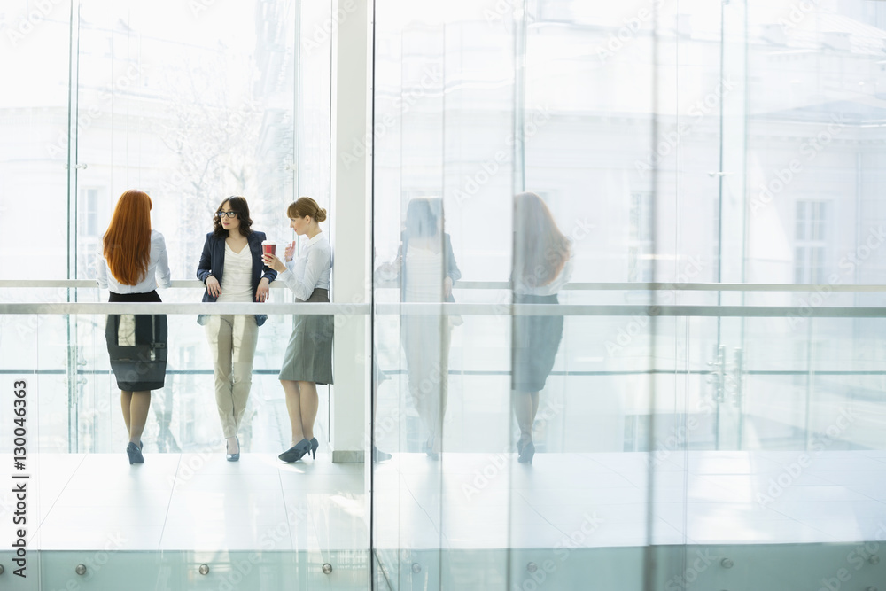 Businesswomen conversing at office hallway Businesswomen conversing at office hallway