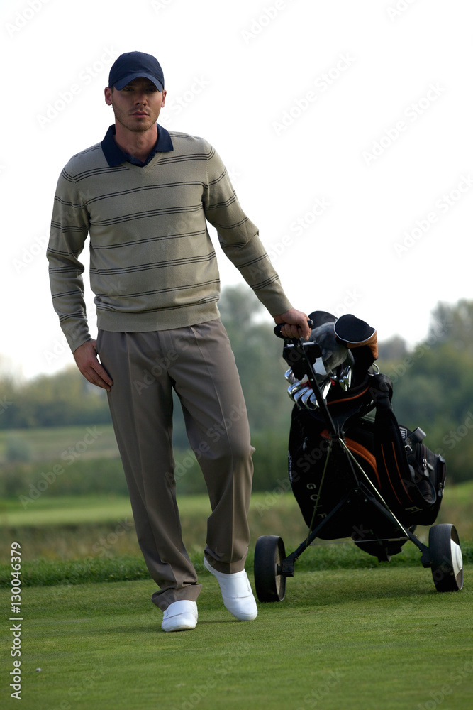 Portrait of young man carrying trolley with golf bag Portrait of young man carrying trolley with golf bag