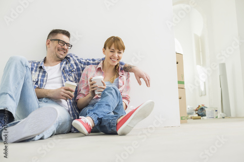 Full-length of cheerful couple with coffee cups in new house