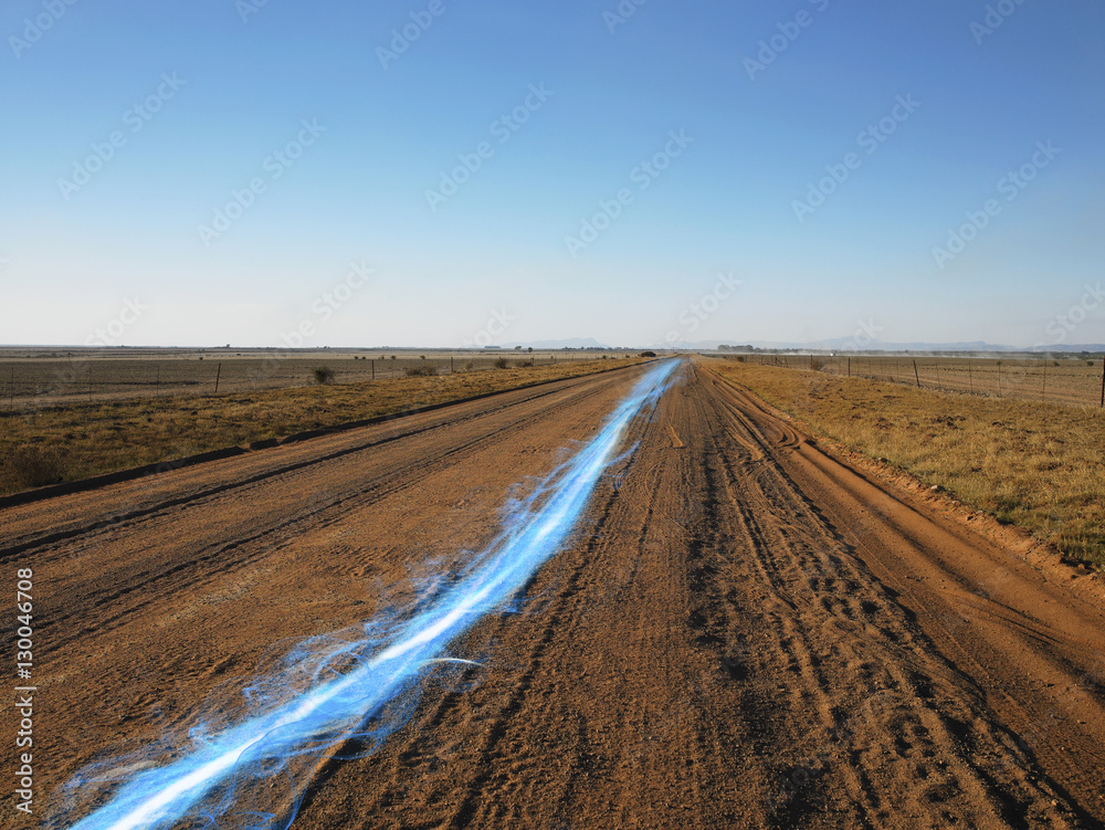 Naklejka premium Blue streak of light on dirt road against clear sky