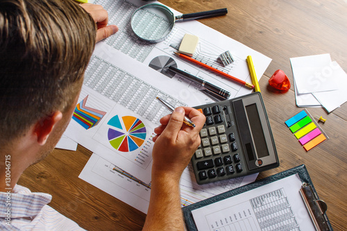 Business analysis - calculator, sheet, graphs (business report) and analyst hand, top view photo