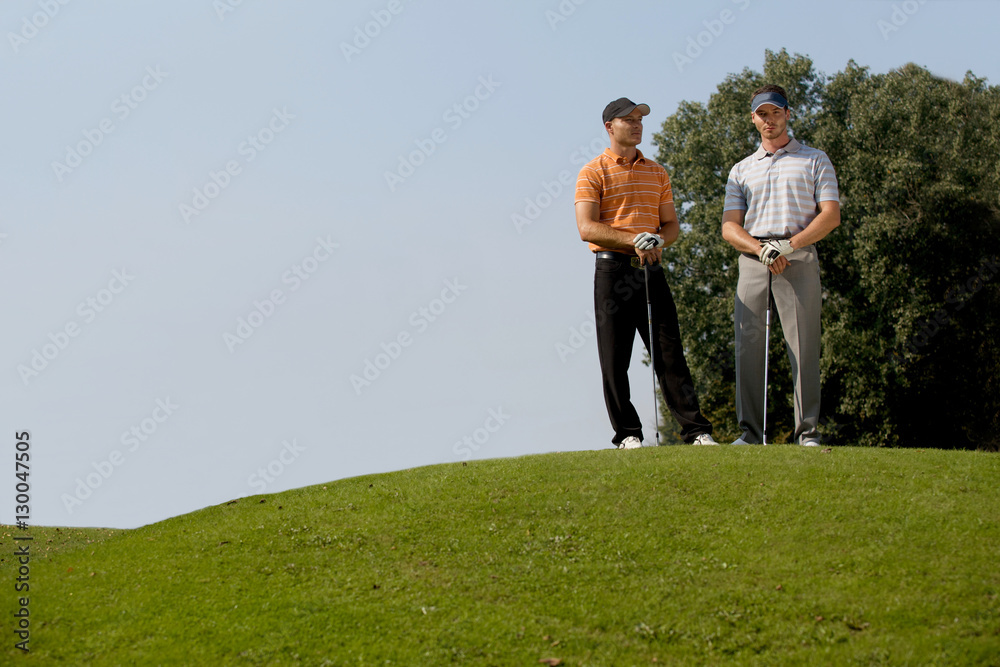 Portrait of young men standing with golf sticks on golf course Portrait of young men standing with golf sticks on golf course