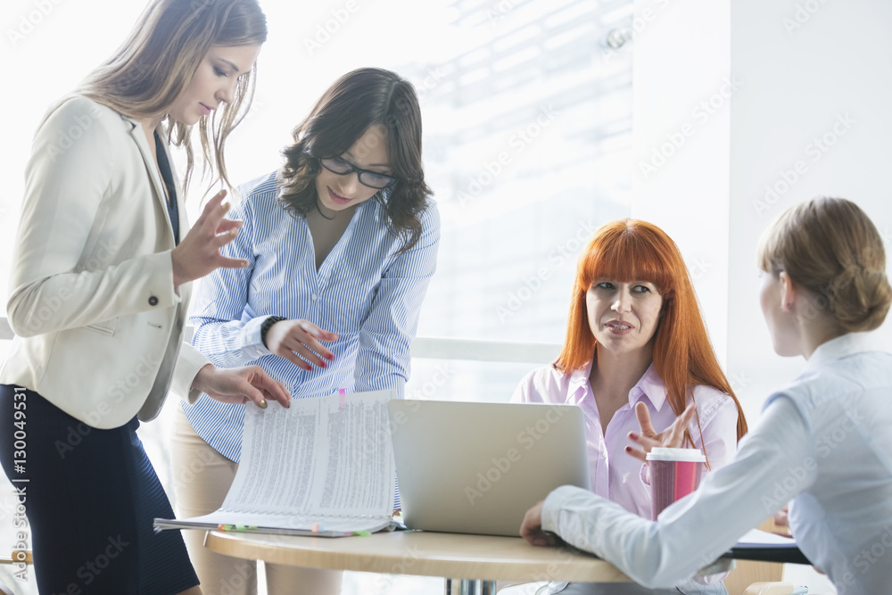 Businesswomen discussing over documents at table in office