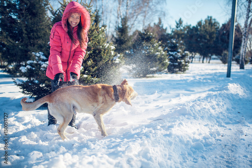 Woman with a dog Labrador playing in winter outdoors