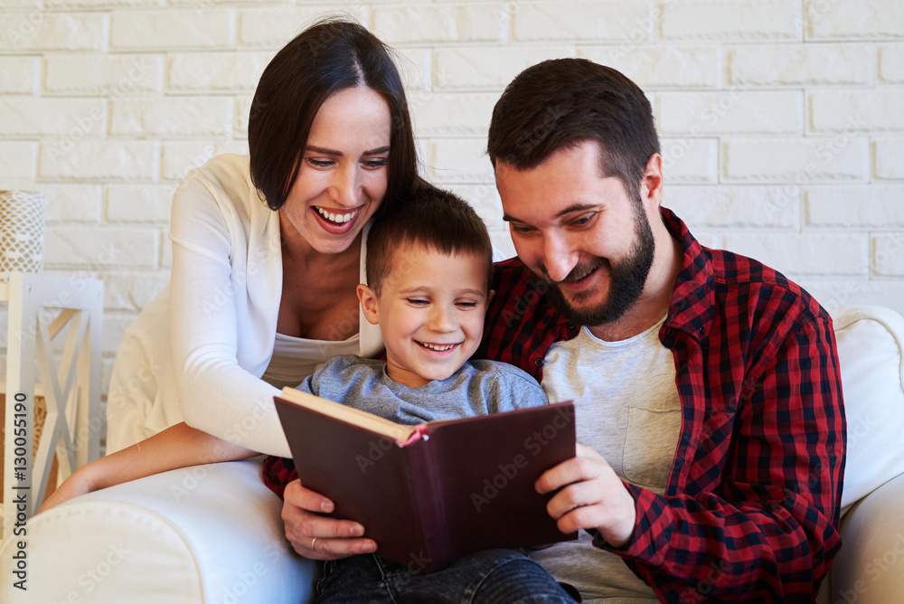 Family laughing together while reading a funny book Family laughing together while reading a funny book