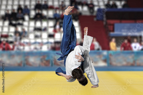 Judokas fighters fighting men on fans background