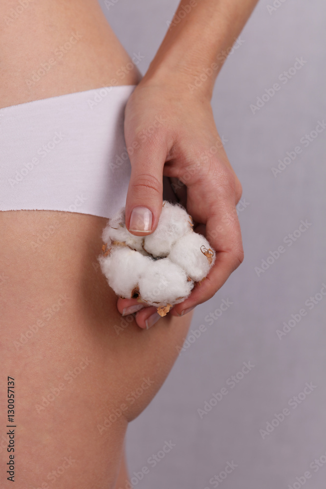 Woman wearing cotton panties and holding cotton flower close up. Female underwear made from natural organic materials Woman wearing cotton panties and holding cotton flower close up. Female underwear made from natural organic materials