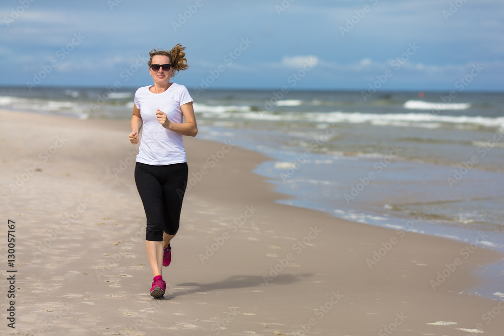 Middle-aged woman running on beach 