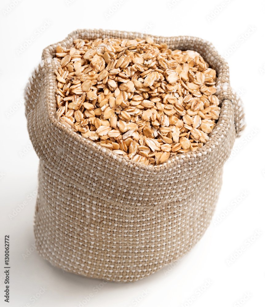Burlap sack filled oats on white background. Healthy food. Close up, top view, high resolution product Burlap sack filled oats on white background. Healthy food. Close up, top view, high resolution product