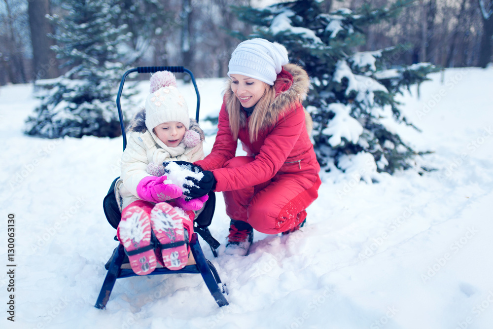 Happy mother and baby playing outdoors in winter