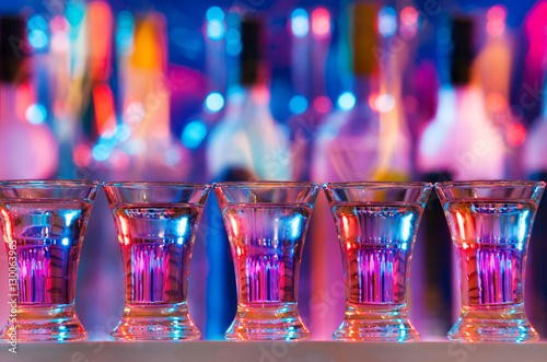 Five burning drinks in shot glasses on bar counter photo