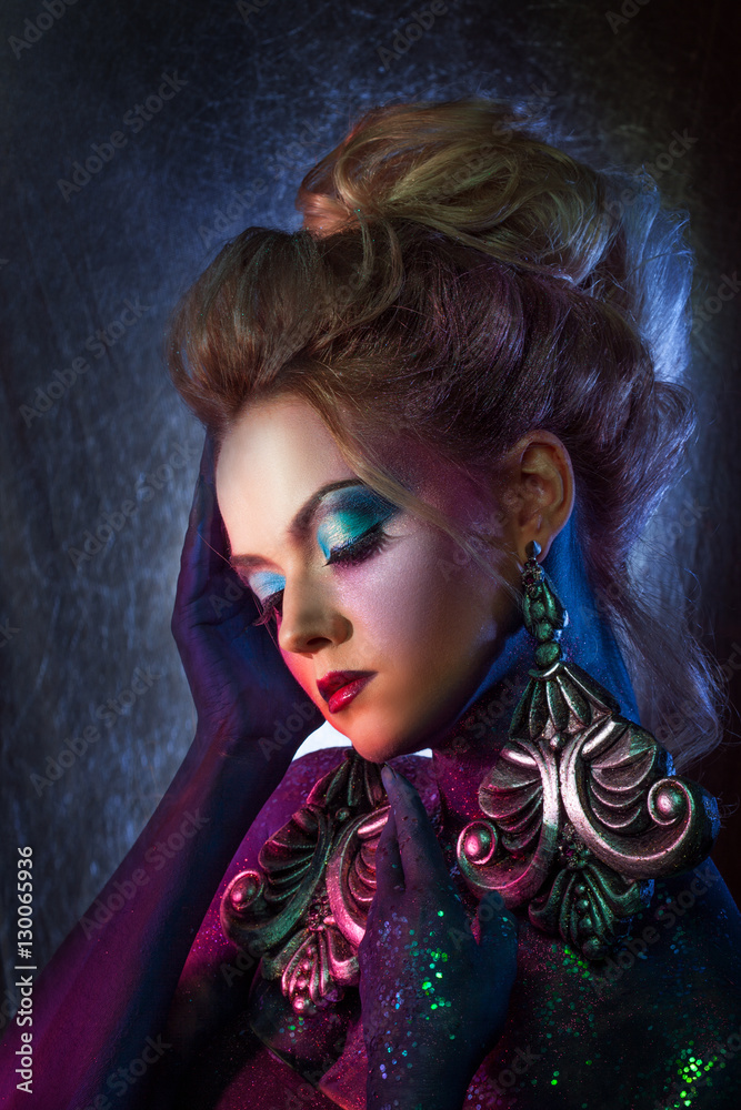 Young attractive blonde girl in bright art-makeup, high hair, body painting. Rhinestones and glitter Young attractive blonde girl in bright art-makeup, high hair, body painting. Rhinestones and glitter