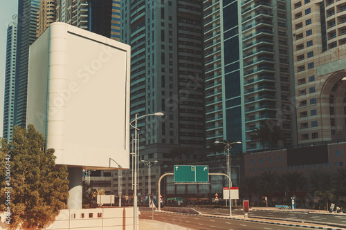 Mock up of blank vertical white advertising billboard in Dubai with residential and office modern contemporary skyscrapers and empty highway behind
