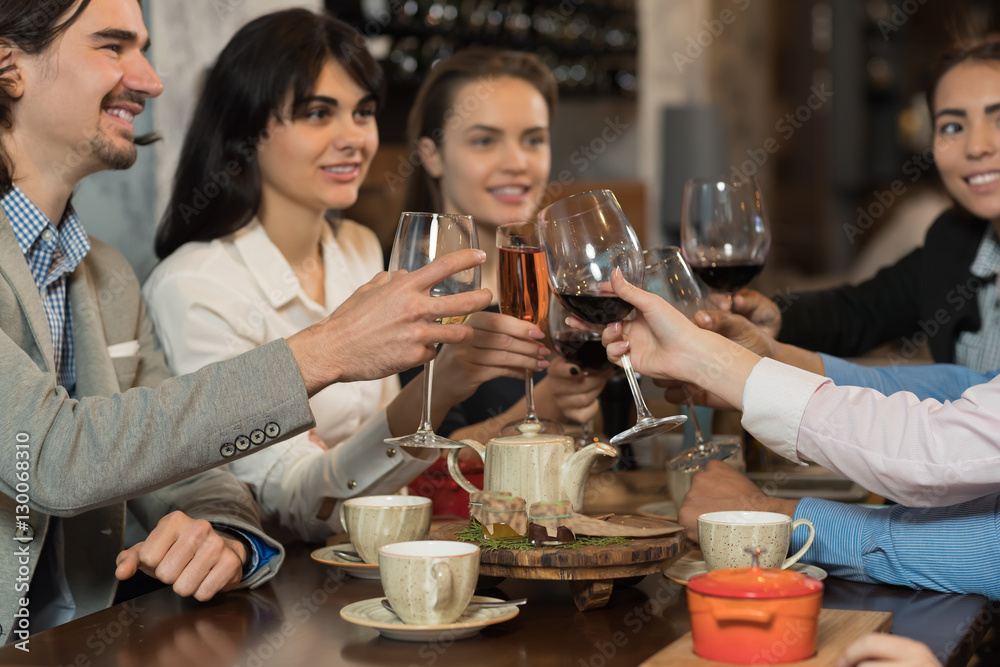 Young Business People Group Drink Wine Sitting Restaurant Table, Friends Hold Glasses Clink Toasting Smiling Mix Race Men Women