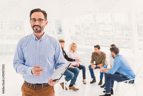 Smiling psychologist standing and holding questionnaire