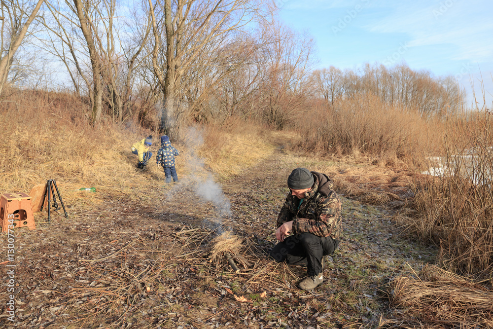 a man a fire outdoors in late autumn