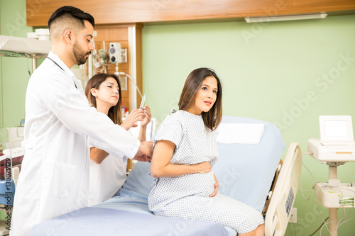 Doctors giving shot to pregnant woman