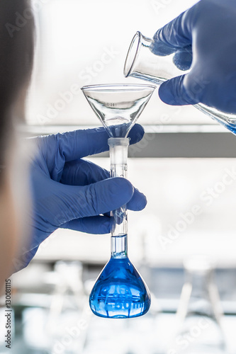 Laboratory technician performs tests and pouring blue liquid
