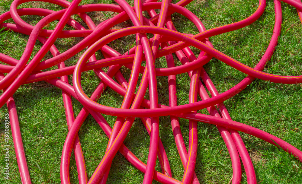 Red hose, messy hose on green grass