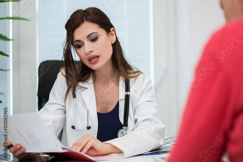 Doctor speaking to her patient while showing some documents