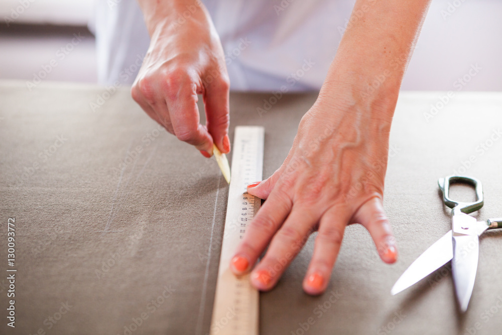 Close up. Hands woman Tailor working cutting a roll of fabric on