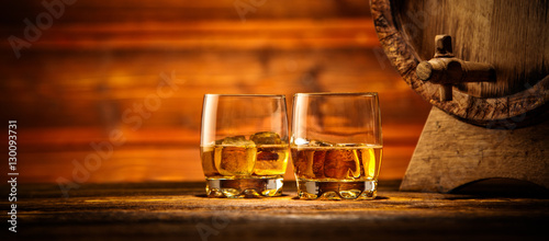 Glasses of whiskey with ice cubes served on wood