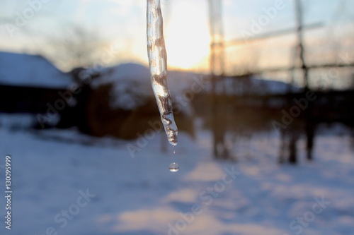 An icicle is backed by a colorful winter sunset sky.