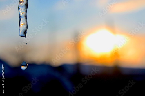 An icicle is backed by a colorful winter sunset sky.