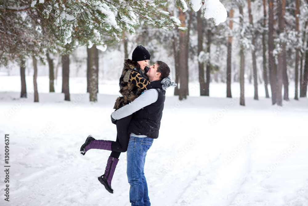 Winter couple, young woman and man hugging in snowy winter day