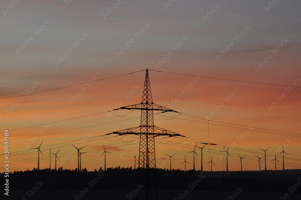 Strommast und Windräder vor Sonneuntergang