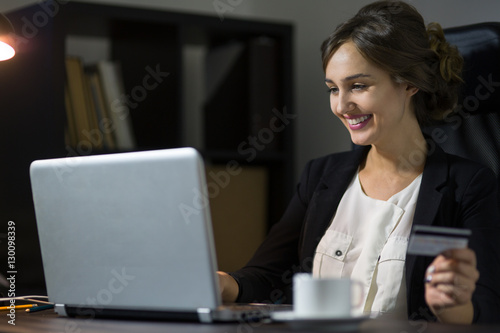 businesswoman sitting at her workplace in office and using credi photo