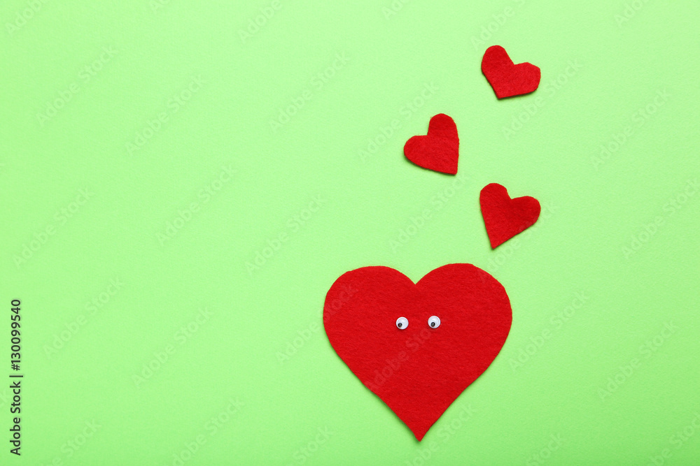 Red heart with googly eyes on a green background