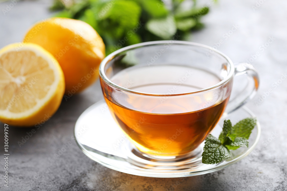 Cup of tea with mint and lemon on grey wooden table Cup of tea with mint and lemon on grey wooden table