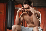 Concentrated man with headache sitting in a gym.