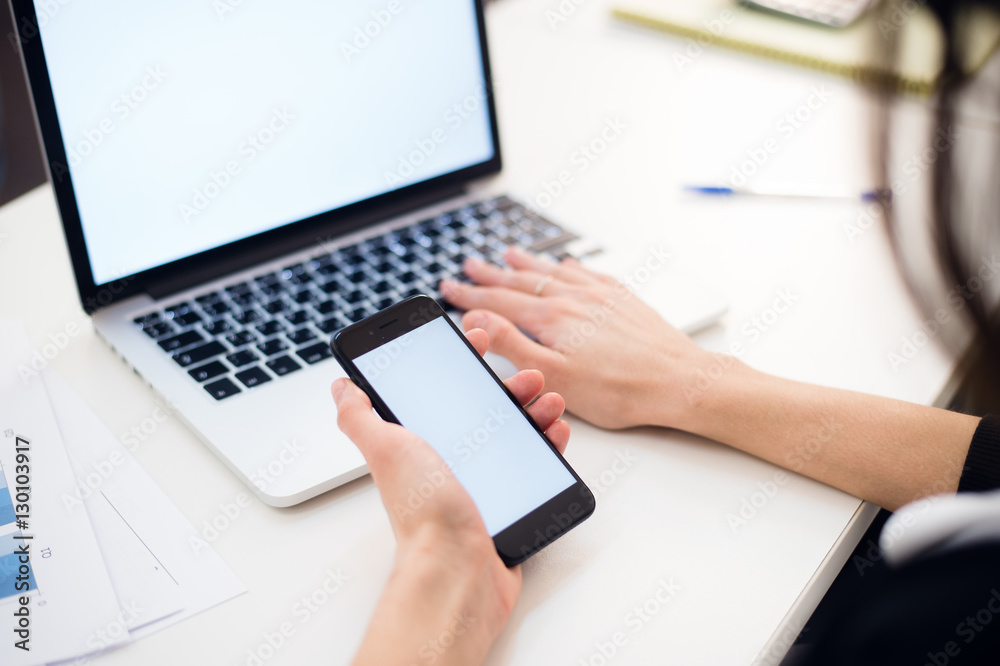 Woman's hands using mobile phone and laptop at the office Woman's hands using mobile phone and laptop at the office