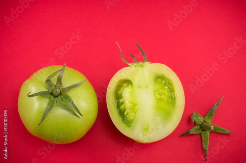 Green tomatoes on red backgeround photo