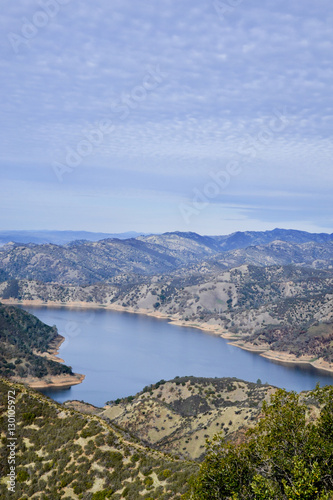 Aerial view of Lake Berryessa from the Blue Ridge Trail on a sunny day, featuring the low water levels of the reservoir, and the surrounding blue oak woodland