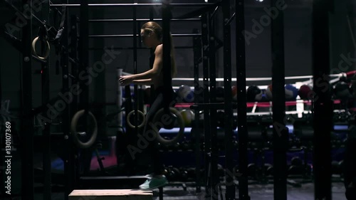 Young strong woman with perfect fitness body in sportswear doing set of box jumps at the gym. Girl jumping into wooden boxes in a training.
