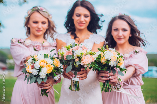Bride with beautiful bridesmaids in lilac color dresses holding bouquets. Autumn in the Park. Sunny day. Close up. Copy space. 